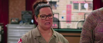 Movie still from “Ghostbusters” (2016), directed by Paul Feig – A woman wearing glasses and a brown shirt; Close Up shot, Over the shoulder angle