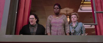 Movie still from “Ghostbusters” (2016), directed by Paul Feig – A group of people standing next to each other on a stage; Medium shot, Low angle