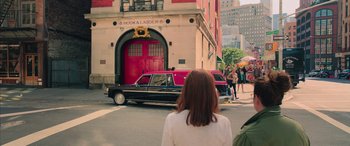 Movie still from “Ghostbusters” (2016), directed by Paul Feig – A woman standing in front of a red fire truck; Wide shot, Over the shoulder angle