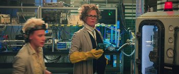Movie still from “Ghostbusters” (2016), directed by Paul Feig – A woman in a lab coat holding a cell phone in her hands; Medium shot, Low angle