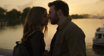 Movie still from “Ghosted” (2023), directed by Dexter Fletcher – A man and a woman kissing in front of a body of water; Close Up shot, Low angle