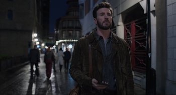 Movie still from “Ghosted” (2023), directed by Dexter Fletcher – A man walking down a street holding a cell phone; Medium shot, Low angle