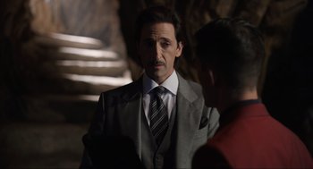 Movie still from “Ghosted” (2023), directed by Dexter Fletcher – A man wearing a suit and tie talking to another man wearing a suit and tie; Medium shot, Over the shoulder angle