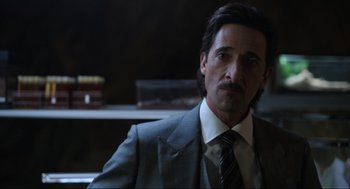 Movie still from “Ghosted” (2023), directed by Dexter Fletcher – A man wearing a suit and tie in a room; Close Up shot, Low angle