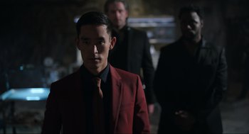 Movie still from “Ghosted” (2023), directed by Dexter Fletcher – A man in a red jacket and a black tie; Medium shot, Over the shoulder angle