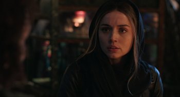 Movie still from “Ghosted” (2023), directed by Dexter Fletcher – A young woman with long brown hair wearing a hooded jacket; Close Up shot, Over the shoulder angle