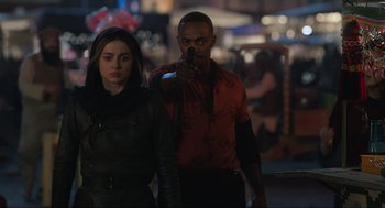 Movie still from “Ghosted” (2023), directed by Dexter Fletcher – A man and a woman standing next to each other holding a gun; Medium shot, Over the shoulder angle