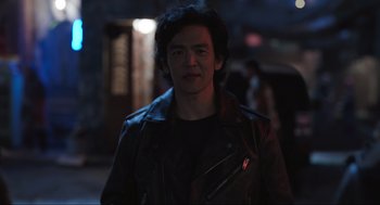 Movie still from “Ghosted” (2023), directed by Dexter Fletcher – A man wearing a leather jacket standing in the dark; Medium shot, Over the shoulder angle