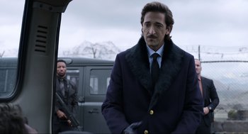 Movie still from “Ghosted” (2023), directed by Dexter Fletcher – A man in a suit and tie standing next to another man in a suit and tie; Medium shot, Over the shoulder angle