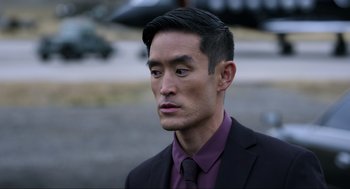 Movie still from “Ghosted” (2023), directed by Dexter Fletcher – A person wearing a suit and tie; Close Up shot, Over the shoulder angle