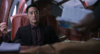 Movie still from “Ghosted” (2023), directed by Dexter Fletcher – A man in a suit sitting in a leather chair; Medium shot, Over the shoulder angle