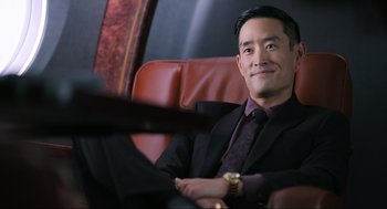 Movie still from “Ghosted” (2023), directed by Dexter Fletcher – A man in a suit sitting in a chair; Medium shot, Over the shoulder angle