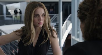 Movie still from “Ghosted” (2023), directed by Dexter Fletcher – A beautiful young woman with long brown hair wearing a black dress; Close Up shot, Over the shoulder angle