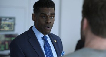 Movie still from “Ghosted” (2023), directed by Dexter Fletcher – A man wearing a suit and tie with blue eyes; Close Up shot, Over the shoulder angle