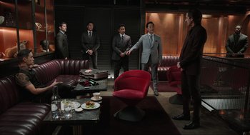 Movie still from “Ghosted” (2023), directed by Dexter Fletcher – A group of men standing around in a room; Wide shot, Over the shoulder angle