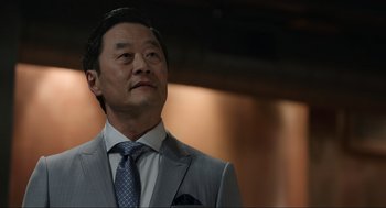 Movie still from “Ghosted” (2023), directed by Dexter Fletcher – A person wearing a suit and a tie; Close Up shot, Low angle