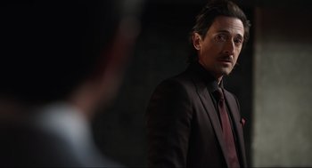 Movie still from “Ghosted” (2023), directed by Dexter Fletcher – A man wearing a suit and a red neck tie; Close Up shot, Over the shoulder angle