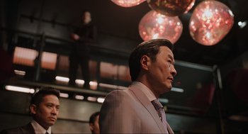 Movie still from “Ghosted” (2023), directed by Dexter Fletcher – A person wearing a suit and tie; Medium shot, Low angle