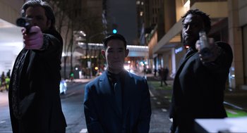Movie still from “Ghosted” (2023), directed by Dexter Fletcher – A man in a blue suit standing on a street; Medium shot, Low angle