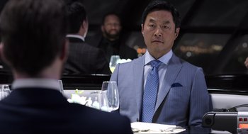 Movie still from “Ghosted” (2023), directed by Dexter Fletcher – A man sitting at a table with a glass of wine in front of him; Medium shot, Over the shoulder angle