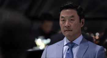 Movie still from “Ghosted” (2023), directed by Dexter Fletcher – A person wearing a suit and a tie; Close Up shot, Over the shoulder angle