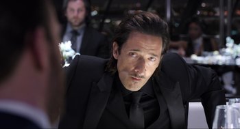 Movie still from “Ghosted” (2023), directed by Dexter Fletcher – A man in a black suit and a black tie; Close Up shot, Over the shoulder angle
