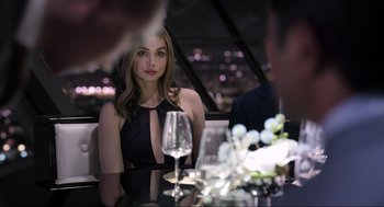 Movie still from “Ghosted” (2023), directed by Dexter Fletcher – A woman sitting at a table with a glass of wine; Medium shot, Over the shoulder angle