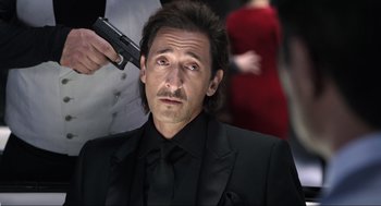 Movie still from “Ghosted” (2023), directed by Dexter Fletcher – A man in a black suit with a gun in his hand; Close Up shot, Low angle