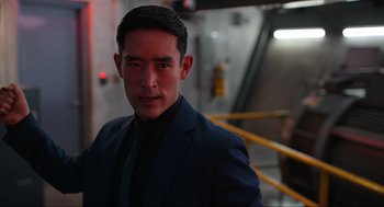 Movie still from “Ghosted” (2023), directed by Dexter Fletcher – A man wearing a suit and tie standing in front of a wall; Close Up shot, Over the shoulder angle