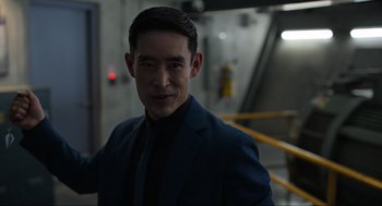Movie still from “Ghosted” (2023), directed by Dexter Fletcher – A man wearing a suit and tie standing in front of a yellow railing; Close Up shot, Over the shoulder angle