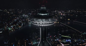 Movie still from “Ghosted” (2023), directed by Dexter Fletcher – A view of a city at night from above; Extreme Wide shot, Overhead angle