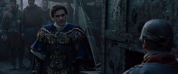 Movie still from “Gladiator” (2000), directed by Ridley Scott – A man dressed as a roman soldier walking in front of a building; Medium shot, Over the shoulder angle