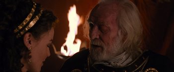 Movie still from “Gladiator” (2000), directed by Ridley Scott – An old man with a white beard is looking at a fire; Close Up shot, Over the shoulder angle