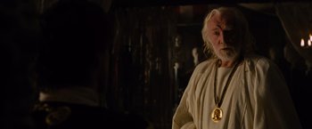 Movie still from “Gladiator” (2000), directed by Ridley Scott – An old man with a long white beard wearing a gold necklace; Close Up shot, Over the shoulder angle