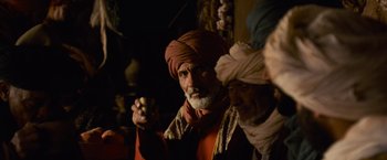Movie still from “Gladiator” (2000), directed by Ridley Scott – A man with a turban and a beard is holding something in his hand; Medium shot, Over the shoulder angle