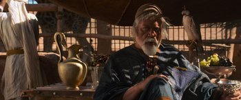 Movie still from “Gladiator” (2000), directed by Ridley Scott – An older man sitting on a chair in a room; Medium shot, Over the shoulder angle