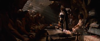 Movie still from “Gladiator” (2000), directed by Ridley Scott – A group of people sitting around a fire in a room; Wide shot, Low angle
