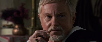 Movie still from “Gladiator” (2000), directed by Ridley Scott – An older man with white hair and a beard is holding a pen in his mouth; Close Up shot, Over the shoulder angle