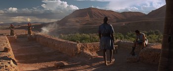Movie still from “Gladiator” (2000), directed by Ridley Scott – A person walking on a dirt path near a mountain; Extreme Wide shot, Low angle