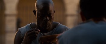 Movie still from “Gladiator” (2000), directed by Ridley Scott – A man is eating something from a plate; Close Up shot, Low angle