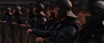 Movie still from “Gladiator” (2000), directed by Ridley Scott – A group of men wearing helmets are lined up in a row; Medium shot, Over the shoulder angle