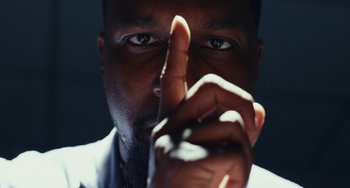 Movie still from “Glass Onion” (2022), directed by Rian Johnson – A person with his finger on his nose; Extreme Close Up shot, Low angle