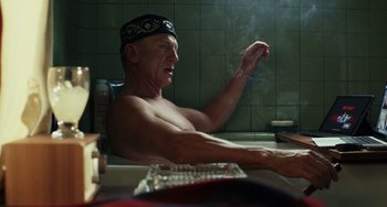 Movie still from “Glass Onion” (2022), directed by Rian Johnson – An older man sitting in a bath tub; Medium shot, Low angle