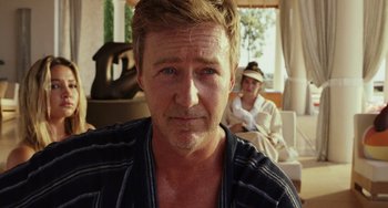 Movie still from “Glass Onion” (2022), directed by Rian Johnson – A person with a person sitting on a couch in the background; Close Up shot, Over the shoulder angle