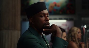 Movie still from “Glass Onion” (2022), directed by Rian Johnson – A man with a beard and a black hat is holding his hand to his face; Close Up shot, Low angle