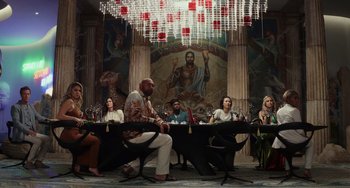 Movie still from “Glass Onion” (2022), directed by Rian Johnson – A group of people sitting around a table; Wide shot, Low angle