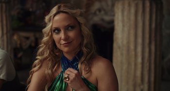 Movie still from “Glass Onion” (2022), directed by Rian Johnson – A beautiful blond woman wearing a green and blue dress; Close Up shot, Over the shoulder angle