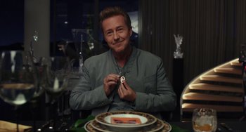 Movie still from “Glass Onion” (2022), directed by Rian Johnson – A man sitting in front of a table holding a cell phone; Close Up shot, Over the shoulder angle