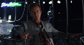 Movie still from “Glass Onion” (2022), directed by Rian Johnson – A man in a gray jacket with blood all over his body; Medium shot, Low angle