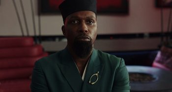 Movie still from “Glass Onion” (2022), directed by Rian Johnson – A man with a beard wearing a green jacket; Close Up shot, Low angle